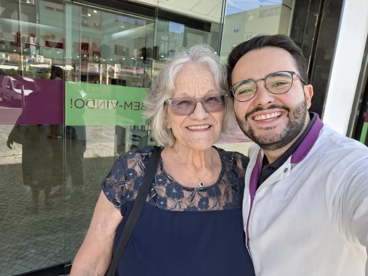 Maria Hilarina, utente há 46 anos, com um farmacêutico da Farmácia Leitão Ribeiro, a sorrir.