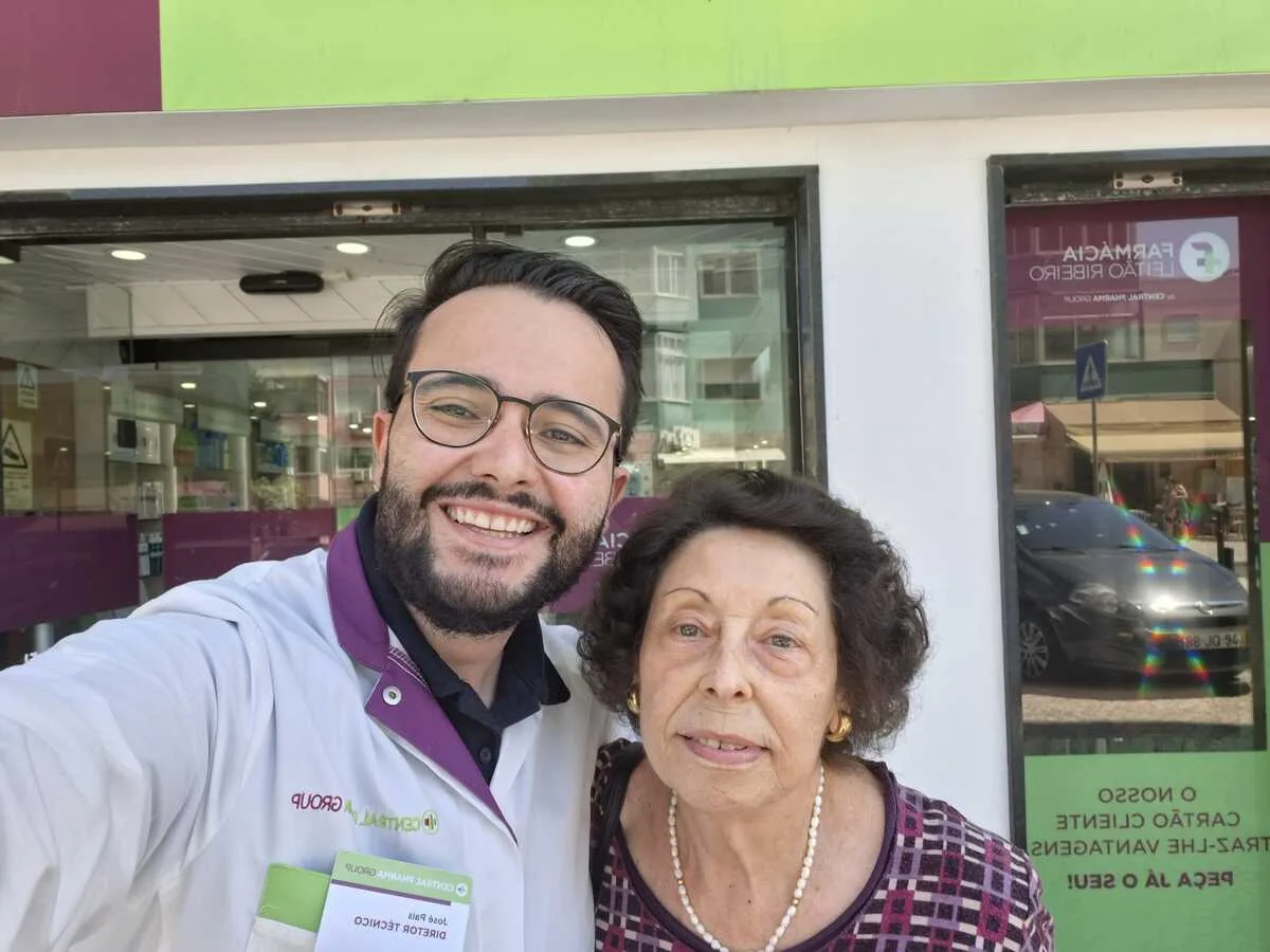 Maria Lina Sotto Mayor ao lado de um farmacêutico da Farmácia Leitão Ribeiro, ambos a sorrir.
